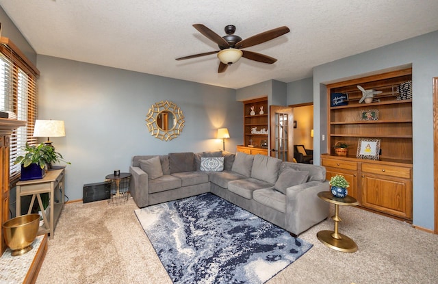 carpeted living area featuring a textured ceiling, built in shelves, and ceiling fan