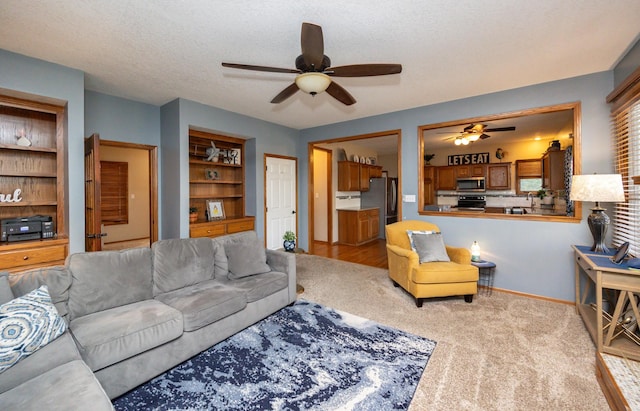 living room with carpet flooring, baseboards, a textured ceiling, and a ceiling fan