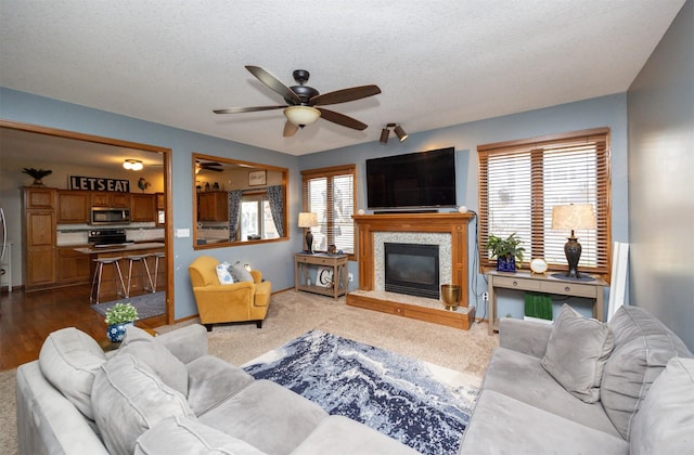 living area with a premium fireplace, baseboards, a textured ceiling, and a ceiling fan