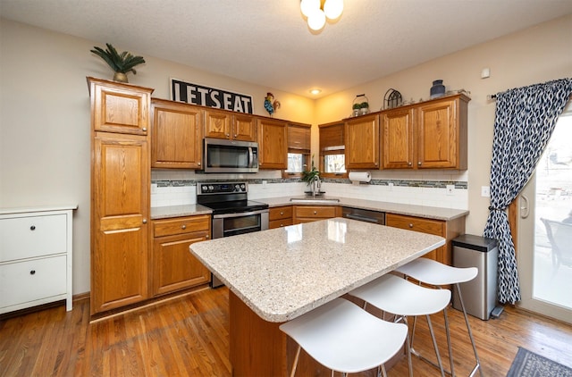 kitchen featuring decorative backsplash, brown cabinets, appliances with stainless steel finishes, and a center island