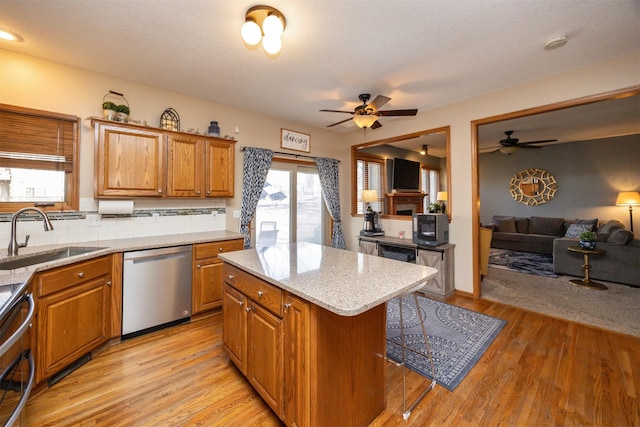 kitchen with a sink, open floor plan, dishwasher, and ceiling fan