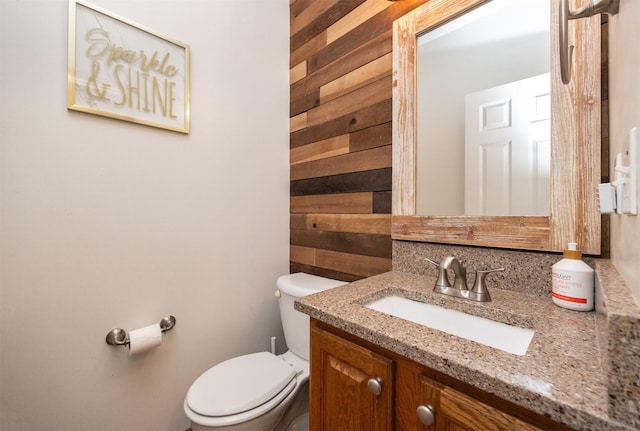 half bath featuring vanity, toilet, and wood walls