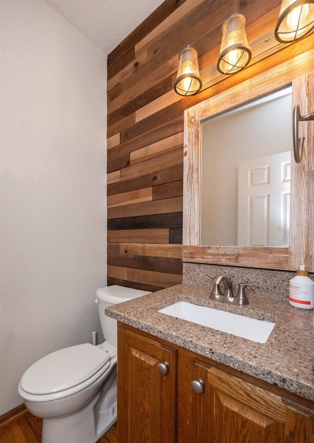 bathroom with wooden walls, vanity, and toilet