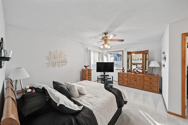 bedroom featuring baseboards, light carpet, a textured ceiling, and ceiling fan