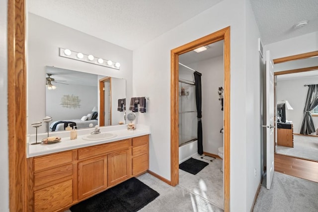 ensuite bathroom with vanity, a ceiling fan, ensuite bath, a textured ceiling, and toilet