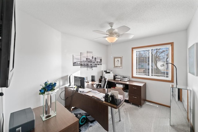 office featuring a textured ceiling, a ceiling fan, baseboards, and light carpet