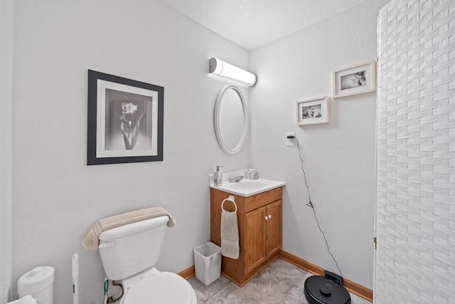 bathroom featuring toilet, vanity, and baseboards