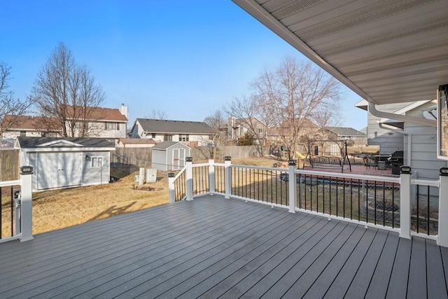 wooden deck with an outbuilding, a fenced backyard, a residential view, and a shed