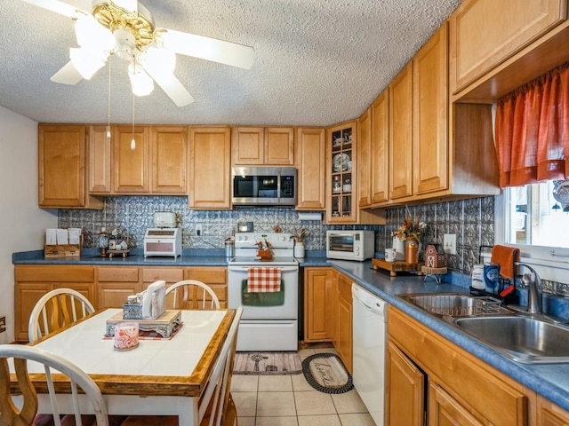 kitchen featuring white appliances, light tile patterned floors, ceiling fan, decorative backsplash, and a sink