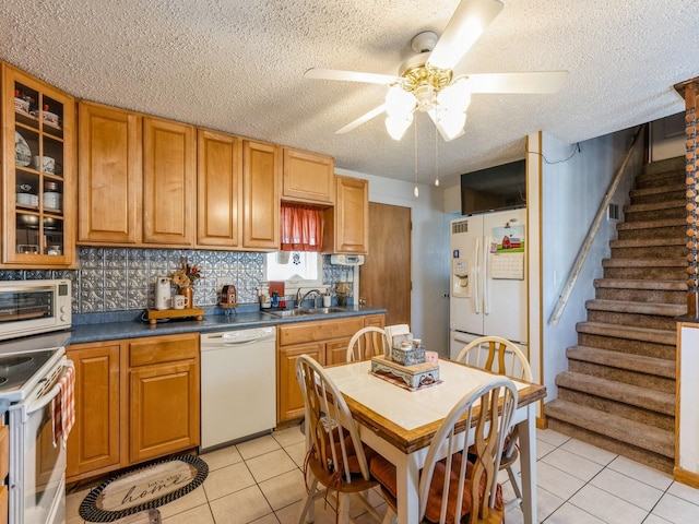 kitchen with white appliances, light tile patterned flooring, a sink, ceiling fan, and backsplash