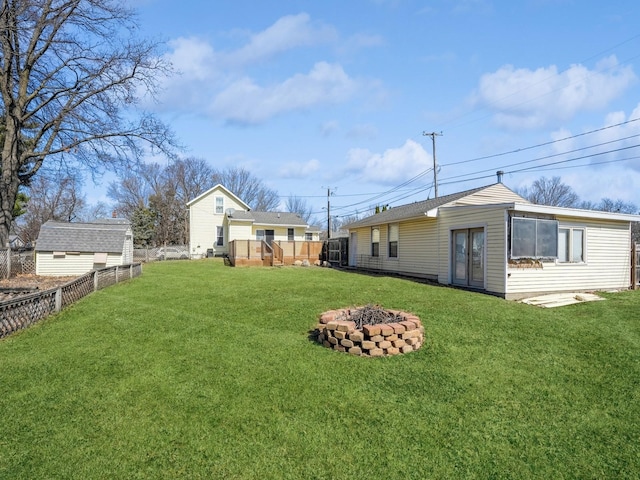 view of yard with an outdoor structure, a fenced backyard, and an outdoor fire pit