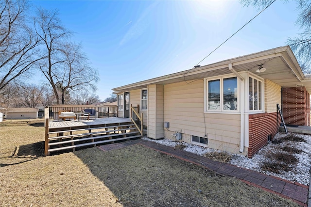 view of side of property with a deck, a yard, and brick siding