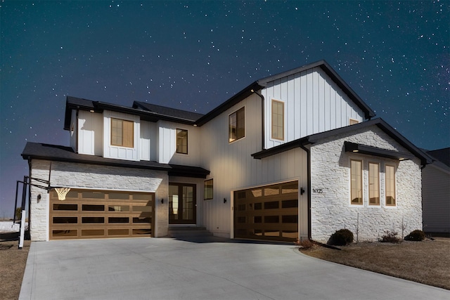 modern farmhouse featuring stone siding, an attached garage, and concrete driveway