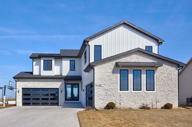 modern farmhouse style home featuring driveway, stone siding, central AC, board and batten siding, and an attached garage