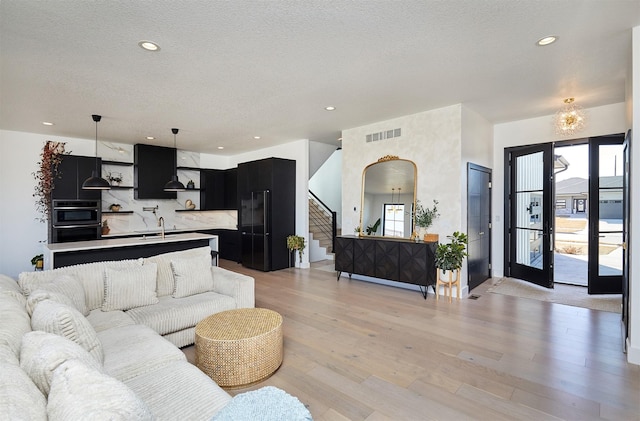 living room featuring stairs, light wood-style floors, visible vents, and a wealth of natural light