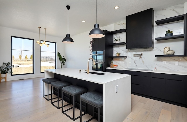 kitchen with a sink, open shelves, light countertops, black appliances, and dark cabinets