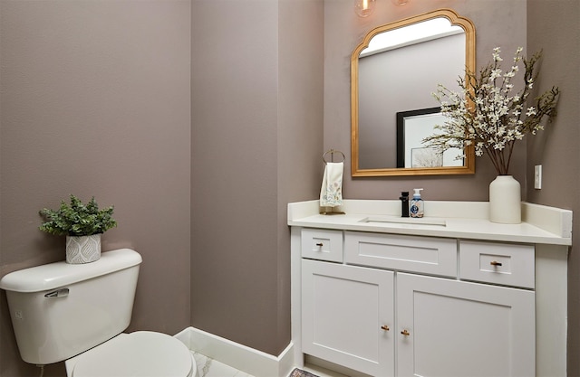 bathroom featuring baseboards, toilet, and vanity