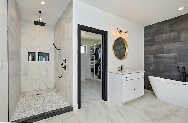 bathroom with a spacious closet, a walk in shower, a freestanding tub, marble finish floor, and vanity