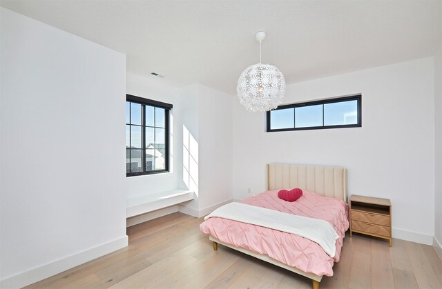 bedroom with visible vents, light wood-style flooring, radiator, baseboards, and a chandelier