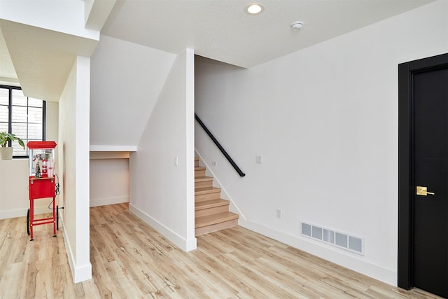 interior space with visible vents, baseboards, light wood-style floors, and stairs