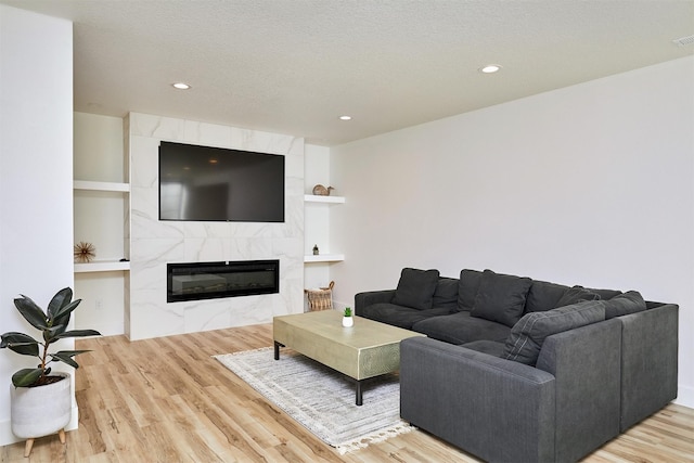 living area featuring a premium fireplace, recessed lighting, a textured ceiling, and wood finished floors