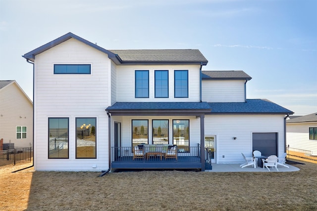 back of property with a patio, a lawn, roof with shingles, and fence