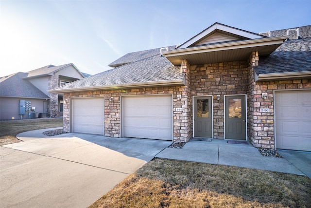 view of front of property with concrete driveway, an attached garage, stone siding, and a shingled roof