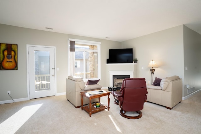 carpeted living area featuring a glass covered fireplace, baseboards, and visible vents