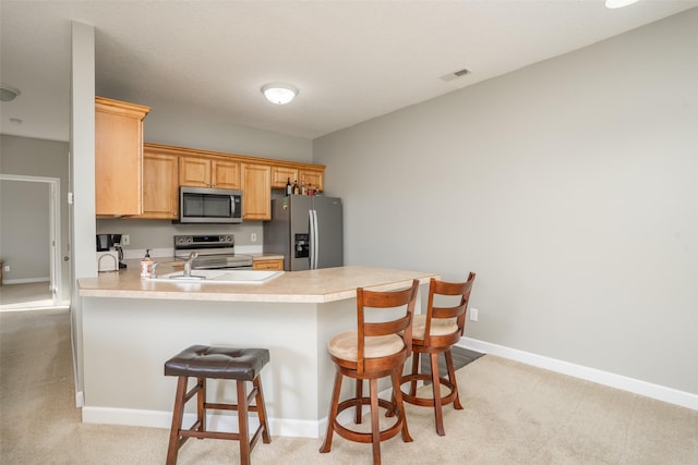 kitchen featuring baseboards, a breakfast bar, a peninsula, stainless steel appliances, and light countertops