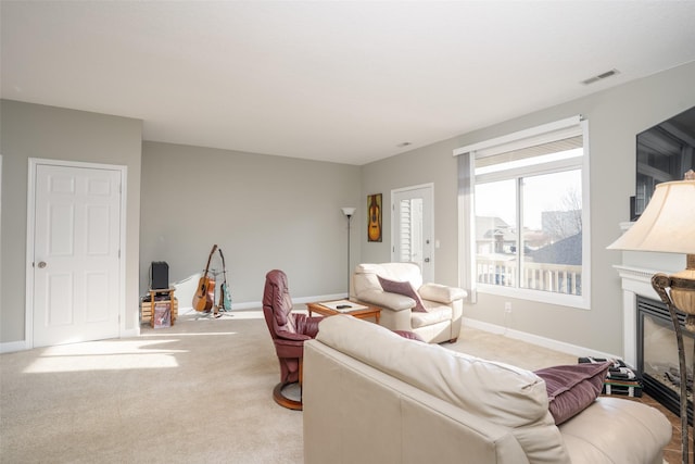 living area featuring visible vents, baseboards, carpet, and a glass covered fireplace