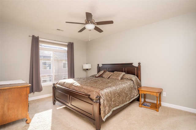 bedroom with visible vents, baseboards, light colored carpet, and ceiling fan