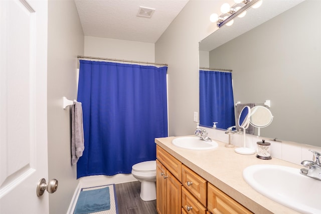 bathroom featuring a textured ceiling, toilet, visible vents, and a sink