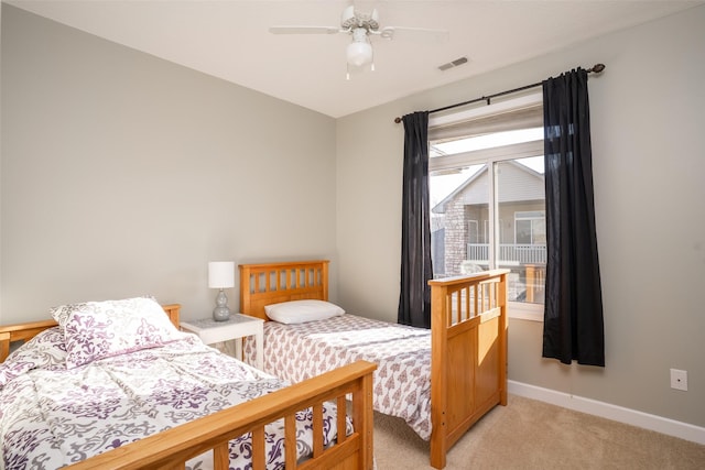 bedroom featuring visible vents, light colored carpet, baseboards, and ceiling fan