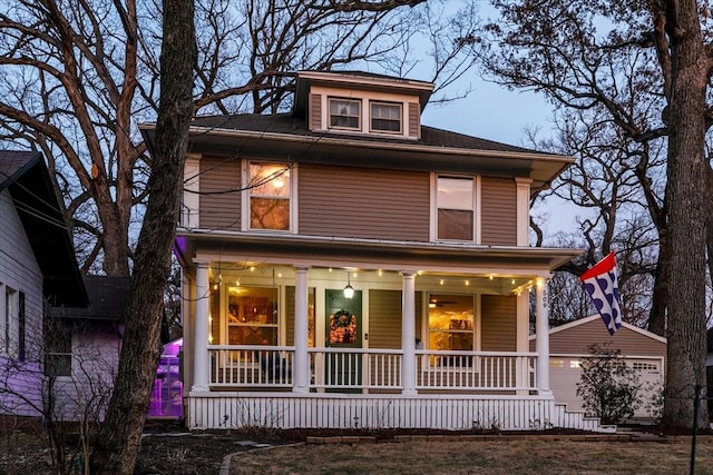 american foursquare style home featuring an outbuilding, a porch, and an attached garage