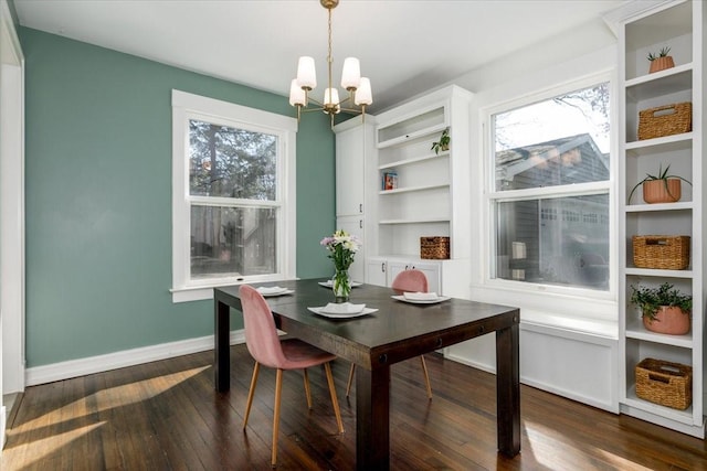 dining space featuring dark wood finished floors, an inviting chandelier, and baseboards