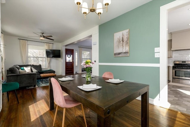 dining space featuring ceiling fan with notable chandelier, baseboards, and wood-type flooring