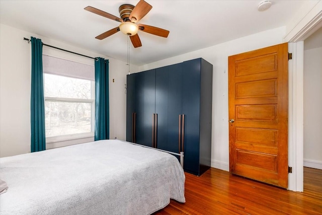 bedroom featuring baseboards, dark wood-type flooring, and ceiling fan