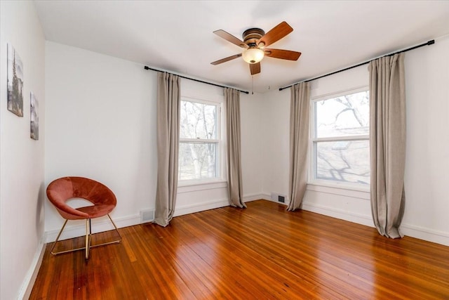 empty room featuring visible vents, baseboards, a ceiling fan, and wood-type flooring