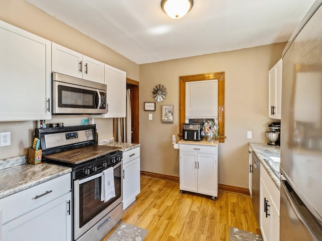 410 1st St S, Newton, IA 50208 - kitchen with light wood-type flooring, baseboards, white cabinets, and stainless steel appliances