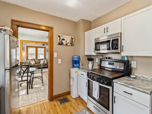 410 1st St S, Newton, IA 50208 - kitchen with visible vents, baseboards, light wood-style floors, stainless steel appliances, and white cabinetry