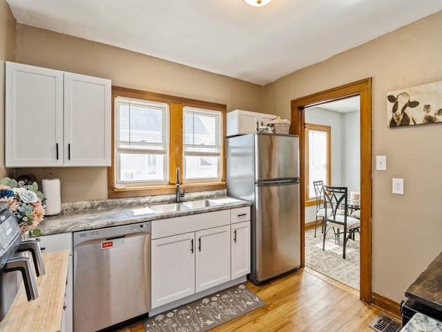 410 1st St S, Newton, IA 50208 - kitchen featuring white cabinets, a sink, light countertops, light wood-style flooring, and stainless steel appliances
