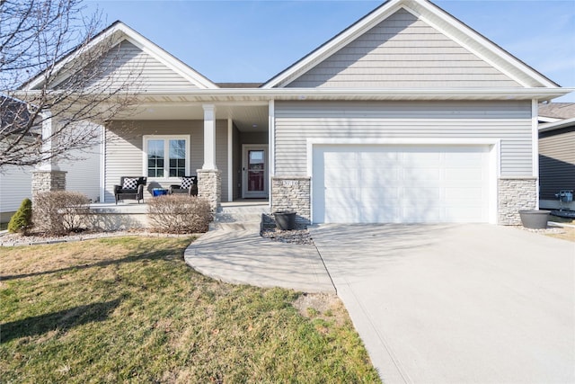 craftsman-style home featuring driveway, stone siding, covered porch, an attached garage, and a front yard