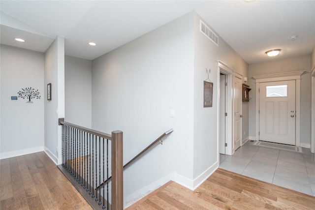 hall featuring visible vents, an upstairs landing, wood finished floors, recessed lighting, and baseboards