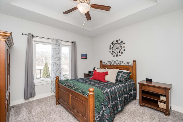 bedroom with baseboards, a raised ceiling, light carpet, and ceiling fan