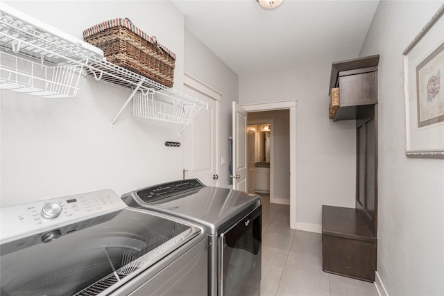 laundry area with baseboards, light tile patterned flooring, washing machine and dryer, and laundry area