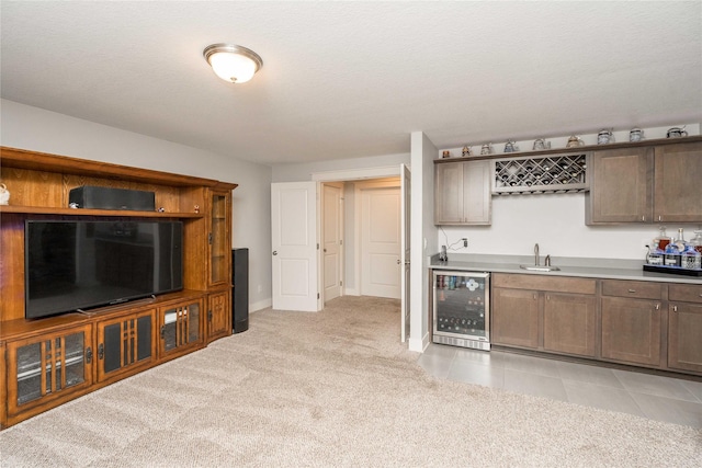 kitchen featuring wine cooler, light countertops, light tile patterned floors, light carpet, and a sink