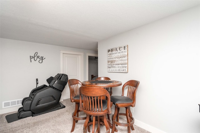 carpeted dining space with visible vents, baseboards, and a textured ceiling