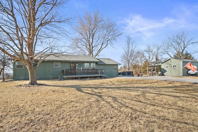 view of front facade with a wooden deck, an outdoor structure, and a front lawn