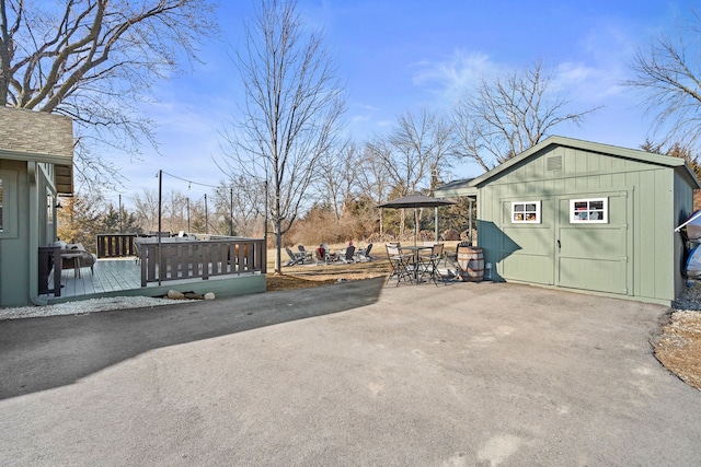 exterior space featuring an outbuilding, a shed, a wooden deck, a gazebo, and a patio area