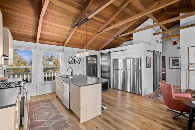 kitchen featuring dark countertops, appliances with stainless steel finishes, a barn door, and a sink